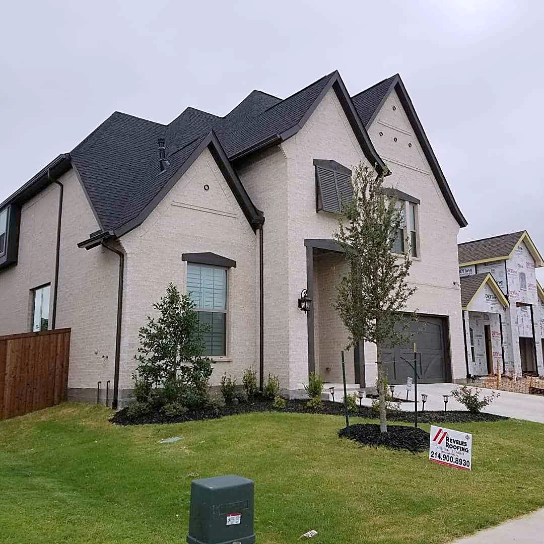 Two-story stone and stucco home with a new charcoal shingle roof