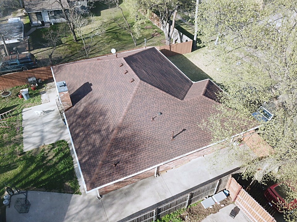 Close aerial of a finished brown shingle roof with the ridge and vents visible